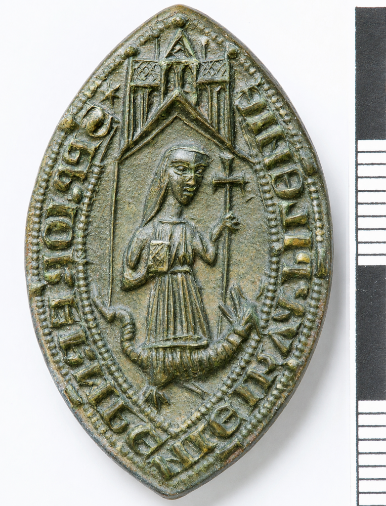 The actual copper-alloy seal matrix of the prior of King’s Lynn’s Friars of the Sack, dating from about 1272–1307. St Margaret of Antioch stands beneath a canopy, holding a cross-staff and trampling the dragon. Portable Antiquities Scheme, FindID 197412.
Photograph: Norfolk County Council/Erica Darch. CC BY-SA 2.0.