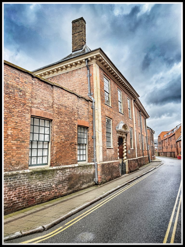 Queen Street, King's Lynn, showing the regularlised line of paving with the original entrance to Clifton House now set back. 
Photo © J.Rye 2025