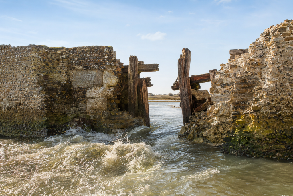 AI generated image of water breeching a medieval harbour wall.